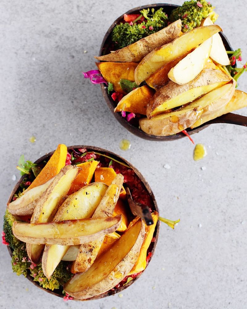 Salad bowls with Salty Baked Vegetables on top, oil drizzled afterwards.