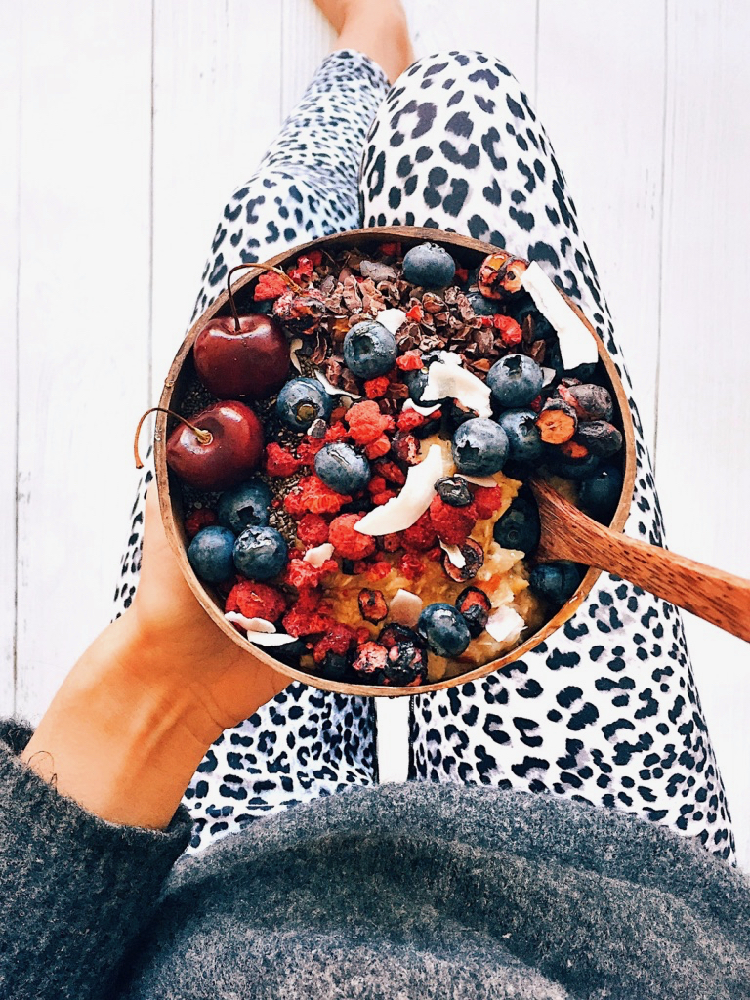 Superfood porridge topped with freeze dried berries, fresh cherries, blueberries, cacao nibs and chia seeds.